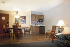 Dining table with four chairs, kitchenette with sink, fridge, and microwave