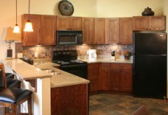 Full kitchen with sink, stove, microwave, fridge, coffee maker, and breakfast bar